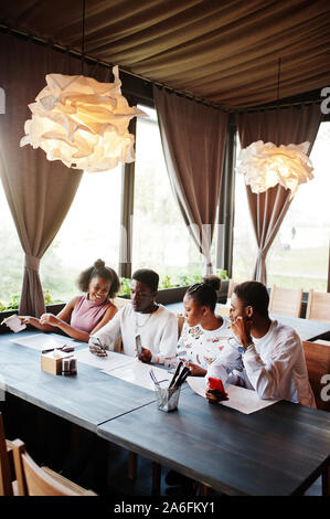 Happy afrikanischen Freunde Sitzen und Chatten im Cafe. Gruppe der schwarzen Völker treffen im Restaurant und an Ihr Mobiltelefon. Stockfoto