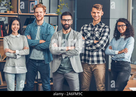 Startupers zusammen arbeiten im Büro stehen gekreuzte Arme suchen Kamera freudige Stockfoto