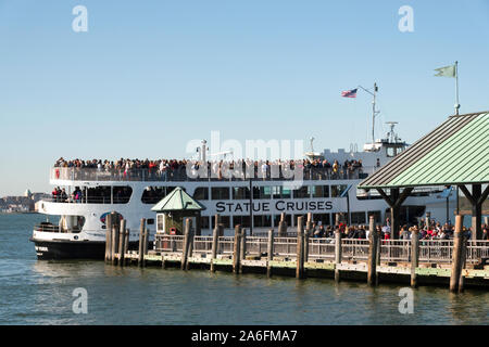 Fähre nach Ellis Island Tour Boot gefüllt mit Touristen kommt im Dock auf Liberty Island Pier, NYC, USA Stockfoto