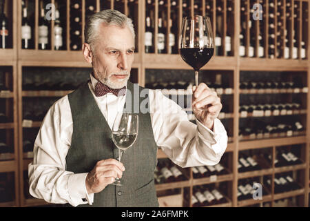 Sommelier Konzept. Älterer Mann mit Brille von Weiß- und Rotwein Kontrolle Klarheit Stockfoto