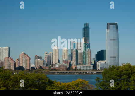 Skyline von Jersey City mit Ellis Island im Vordergrund, den Hafen von New York, New York Stockfoto