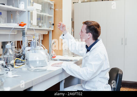 Männliche Wissenschaftler führt chemische Experimente mit Flüssigkeiten in Science Lab Stockfoto