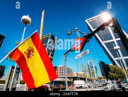 Madrid, Spanien - 26.Oktober 2019: Spanische Flagge im Vordergrund mit Plaza Castilla U-Bahn Eingang befindet sich in der Mitte der Masse und Twin Towers im Hintergrund Stockfoto