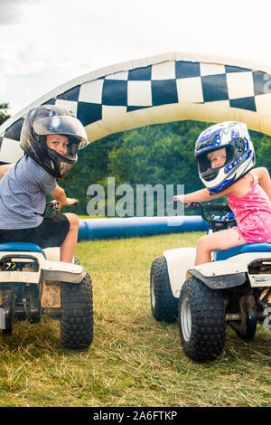 Einen kleinen Jungen mit ADHS, Autismus, Asperger-syndrom reitet ein Quad mit seiner Schwester auf ein Abenteuer Sport Tag für Kinder Stockfoto