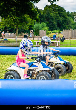 Einen kleinen Jungen mit ADHS, Autismus, Asperger-syndrom reitet ein Quad mit seiner Schwester auf ein Abenteuer Sport Tag für Kinder Stockfoto