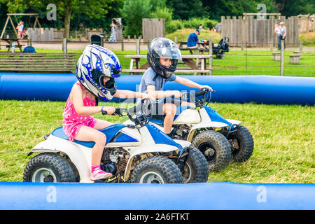 Einen kleinen Jungen mit ADHS, Autismus, Asperger-syndrom reitet ein Quad mit seiner Schwester auf ein Abenteuer Sport Tag für Kinder Stockfoto