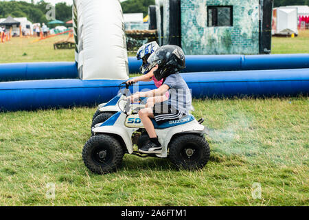 Einen kleinen Jungen mit ADHS, Autismus, Asperger-syndrom reitet ein Quad mit seiner Schwester auf ein Abenteuer Sport Tag für Kinder Stockfoto