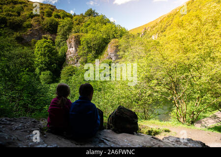 Einen kleinen Jungen mit ADHS, Autismus, Asperger-syndrom, Bruder und Schwester sitzen in einer Höhle hoch in die Berge und bewundern Sie die Aussicht während der Re Stockfoto