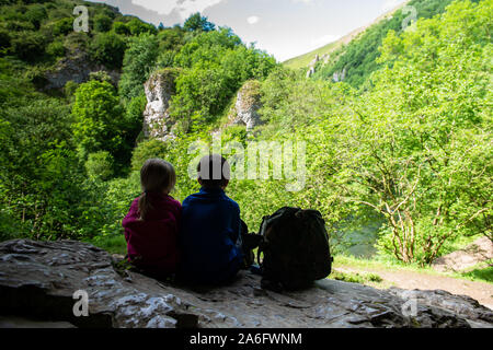 Einen kleinen Jungen mit ADHS, Autismus, Asperger-syndrom, Bruder und Schwester sitzen in einer Höhle hoch in die Berge und bewundern Sie die Aussicht während der Re Stockfoto