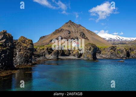 Einsames Haus auf der Basalt Küste in der Nähe der Hafen, hinter dem Berg und den Gletscher Stapafell Snaefelljokull, Arnarstapi, Halbinsel Stockfoto