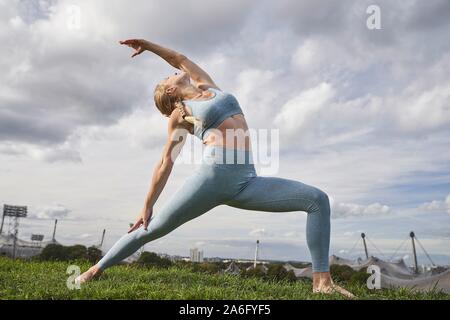 Junge Frau Yoga, Olympiapark, München, Deutschland Stockfoto