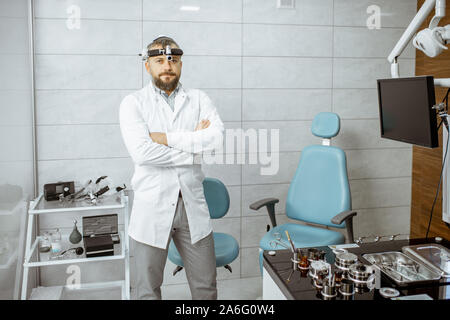 Portrait eines älteren Otolaryngologist stehend in der Arztpraxis mit HNO-Workstation und Diagnosegeräte Stockfoto
