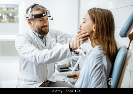 Senior otolaryngologist Prüfung Nase eines jungen Patienten während einer ärztlichen Untersuchung im HNO-Büro Stockfoto