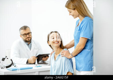 Krankenschwester Unterstützung junger Patienten während einer medizinischen Beratung mit dem Leitenden Arzt im weißen Büro Stockfoto