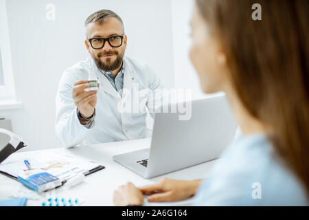 Leitender Arzt einige Medikamente für einen jungen Patienten mit einem Rohr mit dropps in der Arztpraxis Stockfoto
