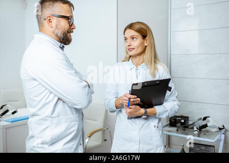 Zwei ältere Ärzte sprechen beim zusammen im Krankenhaus stehen während einer medizinischen Konferenz Stockfoto