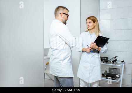 Zwei ältere Ärzte sprechen beim zusammen im Krankenhaus stehen während einer medizinischen Konferenz Stockfoto