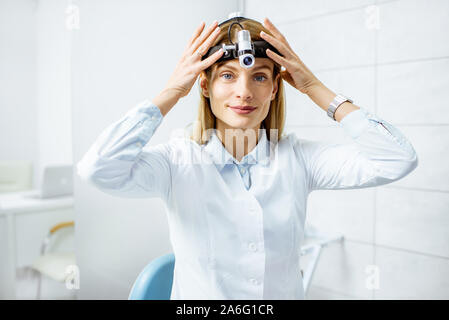 Portrait von einer selbstbewussten weiblichen Otolaryngologist tragen Scheinwerfer an der HNO-Büro Stockfoto