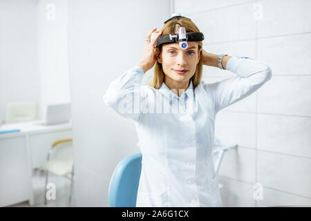 Portrait von einer selbstbewussten weiblichen Otolaryngologist tragen Scheinwerfer an der HNO-Büro Stockfoto