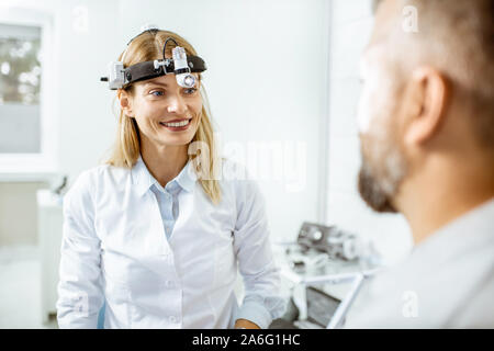 Portrait einer weiblichen zuversichtlich Otolaryngologist während einer medizinischen Beratung mit erwachsenen Patienten an der HNO-Büro Stockfoto