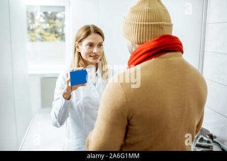 Arzt bietet einige Anti-kalten Hilfsmittel für einen kranken Mann während einer medizinischen Beratung in der Klinik. Halten Sie auf ein Feld mit Leerzeichen einfügen kopieren Stockfoto