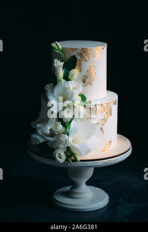 Zwei-klassen-Kuchen mit Blumen auf einem Stand aus Holz auf einem schwarzen Hintergrund Stockfoto