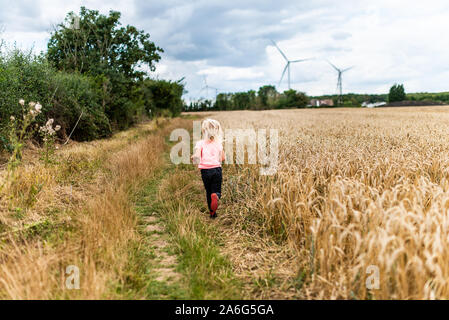 Eine süße kleine blonde Mädchen gehen durch ein Kornfeld, Weizenfeld in der schönen Landschaft Stockfoto