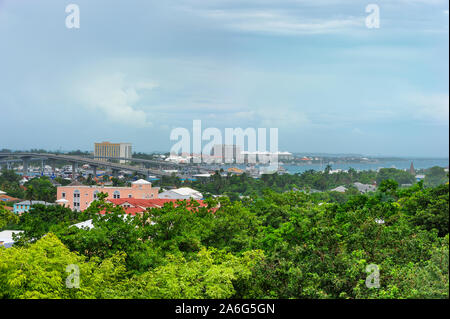 Weite Aussicht von oben auf Bennetts Hill am Fort Fincastle, mit Paradise Island in der Ferne unter stürmischen Himmel. Auf der Dachterrasse eines gelben Bauen Stockfoto