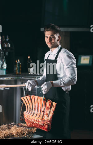 Der Kellner oder Koch erhält trockenes Fleisch im Kühlschrank Stockfoto