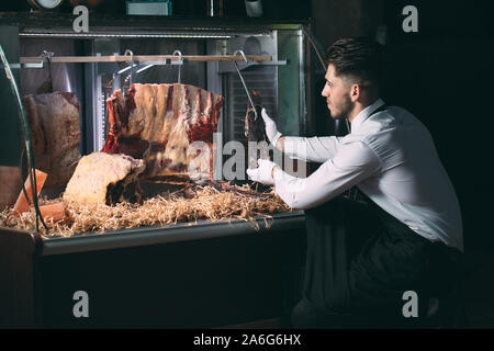Der Kellner oder Koch erhält trockenes Fleisch im Kühlschrank Stockfoto