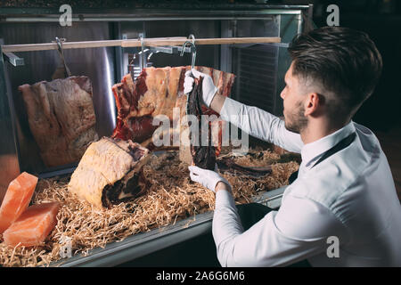 Der Kellner oder Koch erhält trockenes Fleisch im Kühlschrank Stockfoto