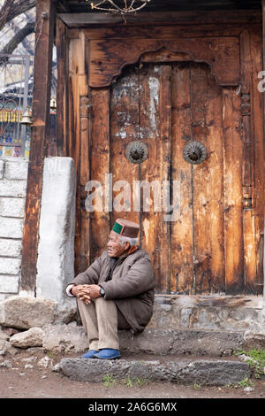 Ein alter Mann beobachtet auf einer Hochzeit Prozession vor der Haustür des alten Tempel, Chitkul, Himachal Pradesh. Stockfoto