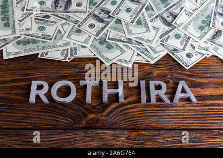 Worte ROTH IRA auf Holz- Oberfläche mit Metall Buchstaben us Papiergeld Stockfoto