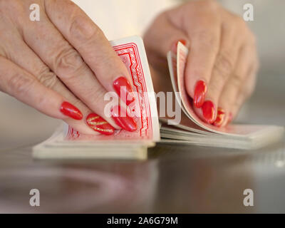 Ein karting Spiel wird mit zwei Hände in speziellen Technik gemischt. Frauen Hände mit gepflegten rot lackierten Fingernägeln mischen die Karten. Close-up und sel Stockfoto