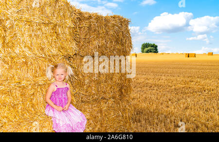 Eine süße kleine blonde Mädchen gehen durch ein Kornfeld, Weizenfeld in der schönen Landschaft Stockfoto