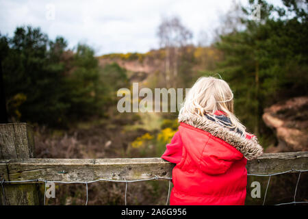 Hübsches kleines Mädchen springen in sehr schlammigen Pfütze das Spielen mit Ihrem Hund in der kalten Herbst Wetter in Stoke-on-Trent, Staffordshire, Hulme Steinbruch Stockfoto