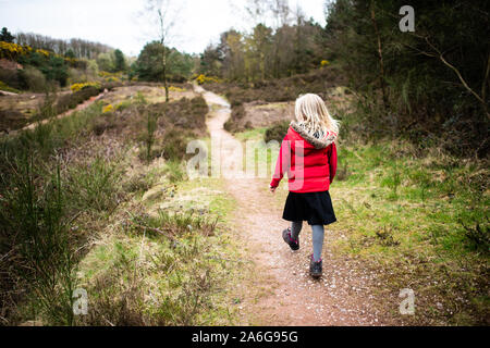 Hübsches kleines Mädchen springen in sehr schlammigen Pfütze das Spielen mit Ihrem Hund in der kalten Herbst Wetter in Stoke-on-Trent, Staffordshire, Hulme Steinbruch Stockfoto