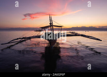 Sonnenuntergang und Fischerboot am Panagsama Beach, Moalboal, Cebu, Visayas, Philippinen. Stockfoto