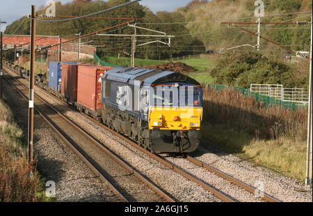 Direct Rail Services (DRS) livrierten Class 66 diesel-elektrische Lok schleppen leicht beladen container Zug auf der West Coast Main Line am 26. Oktober 2019. Stockfoto