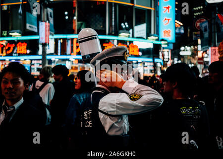 Shibuya, Japan. 26 Okt, 2019. Ein Polizist deckt seine Hörer während Halloween Feiern in Shibuya, Japan am 26. Oktober 2019. Quelle: Lba Co.Ltd./Alamy leben Nachrichten Stockfoto