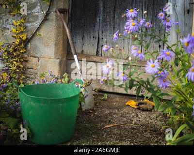 Garten Werkzeuge werden während des Gärtners pause neben einem hölzernen Tür eines Sandstein Gebäude verlassen. Stockfoto