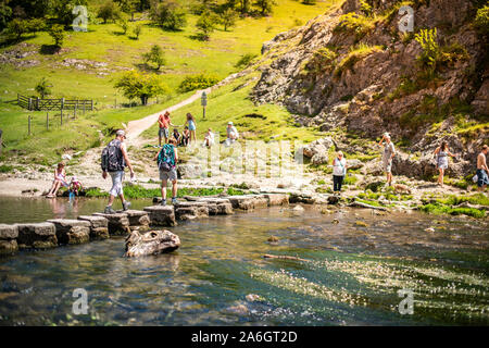 Einen kleinen Jungen und Mädchen hoffen, über die dovedale Trittsteine über einen Fluss, Bach im Peak District National Park, Derbyshire springen, Stockfoto