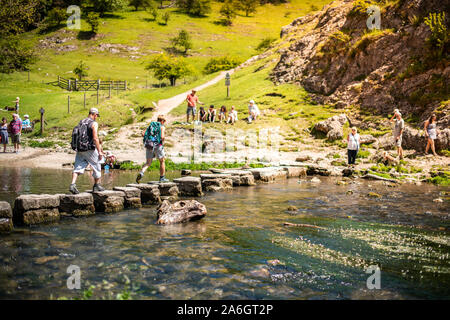 Einen kleinen Jungen und Mädchen hoffen, über die dovedale Trittsteine über einen Fluss, Bach im Peak District National Park, Derbyshire springen, Stockfoto