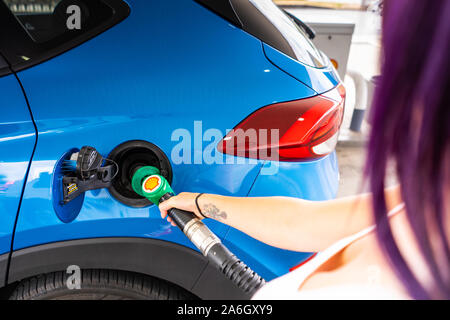 Eine junge schlanke Frauen mit lila Haaren füllt sich Ihr Auto mit bleifreiem Benzin, Shell Tankstelle Stockfoto