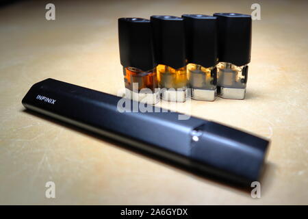 Juul vape Pod elektronische Zigarette Gerät mit einer Packung Marlboro  Zigaretten und eine Zigarette draußen auf eine weiße strukturierte Tabelle  gelegt, isoliert Stockfotografie
