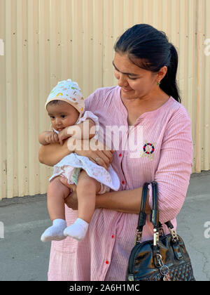 Buchara, Usbekistan - Juli 12, 2019: uzbekistani Mutter und ihr Kind in ihren Armen in den Straßen von Buchara, Usbekistan. Stockfoto