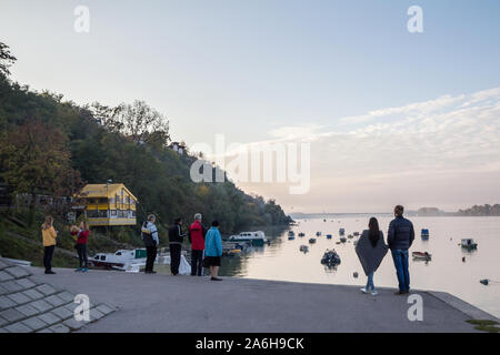 Belgrad, SERBIEN - Oktober 23, 2016: Die Menschen stehen auf Zemun Quay (Zemunski Kej) bei Sonnenuntergang, Sonnenuntergang über der Donau, während Einnahmen Bilder Stockfoto