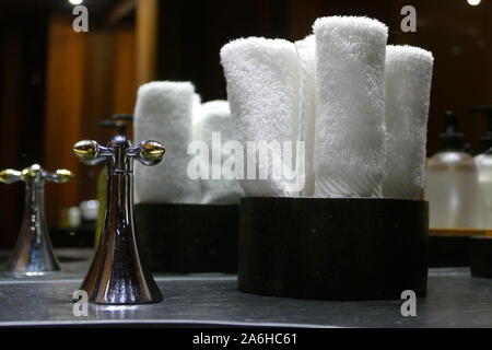 White spa Handtücher ordentlich in Umlauf Weidenkörbe durch Waschbecken Wasserhahn platziert, Detail Stockfoto