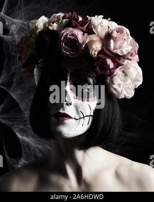 Schöne Mädchen mit traditionellen mexikanischen Tod Maske. Calavera Catrina. Sugar Skull Make-up. Mädchen in einem Kranz von Rosen auf dem Hintergrund der weiss w gekleidet Stockfoto