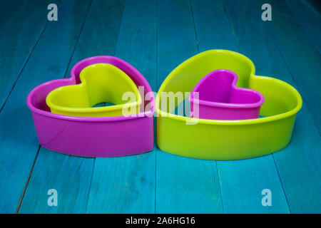 Farbige herzförmige Ausstechform Figuren sitzen auf Blau Holz- Hintergrund und niedrigen Winkel gesehen Stockfoto